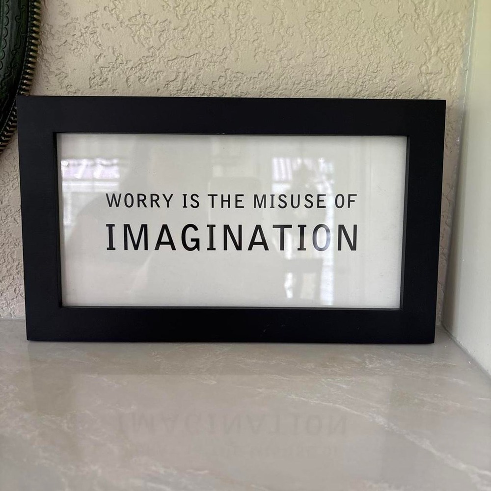 Black framed "Worry is the Misuse of Imagination" sign